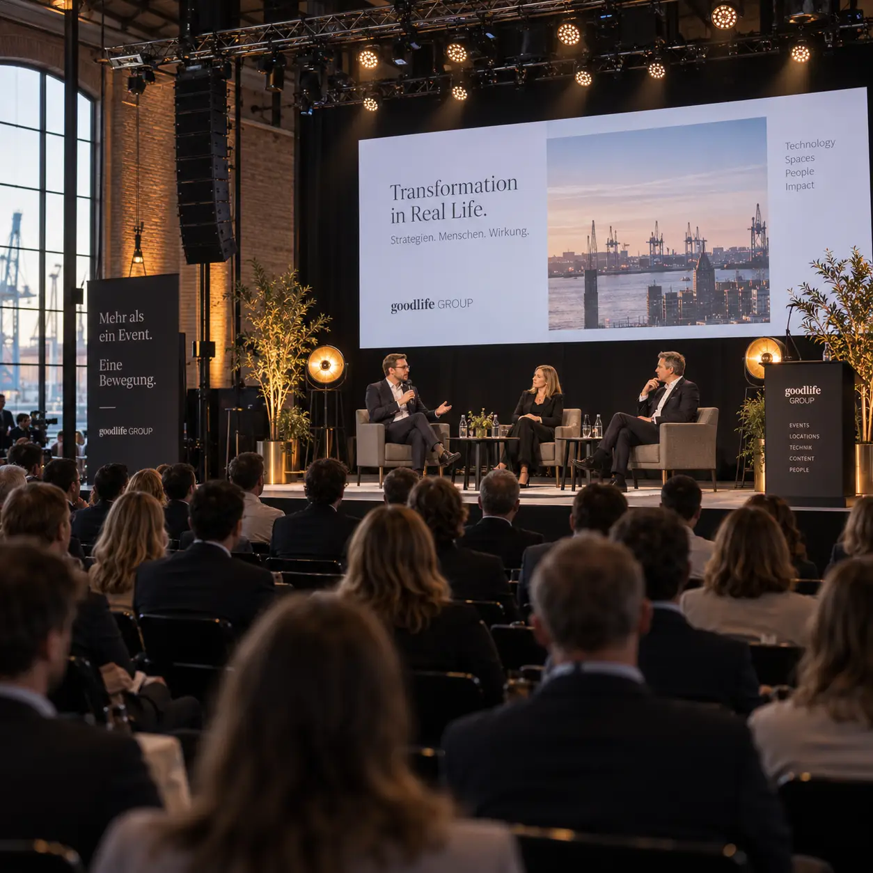 Panel auf einer Bühne mit Konferenztechnik und Publikum